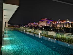 una piscina frente a un edificio por la noche en Bell Family Suite @Sepang Kota Warisan KLIA, en Sepang