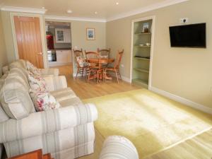 a living room with two couches and a dining room at Bryn Y Don Cottage in Benllech