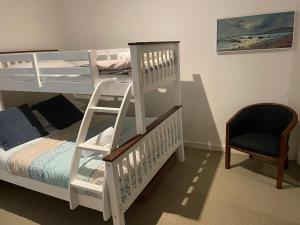 a bedroom with two bunk beds with a ladder and a chair at C-Scape water front apartment in Cowes