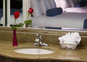 a bathroom sink with a mirror and a red rose at Regency Inn in Los Angeles in Los Angeles