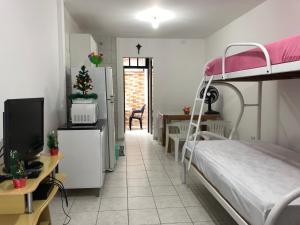 馬蒂尼奧斯的住宿－250m da praia-Kitinete com Piscina-Matinhos-PR，一间卧室配有一张双层床、一张桌子和一台电视。