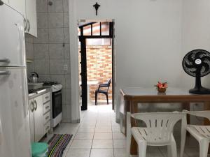 a kitchen with white appliances and a table and chairs at 250m da praia-Kitinete com Piscina-Matinhos-PR in Matinhos