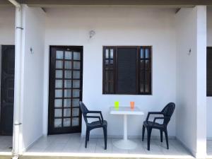 馬蒂尼奧斯的住宿－250m da praia-Kitinete com Piscina-Matinhos-PR，一张白色的桌子和两把椅子、一张桌子和一个窗口