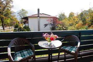 twee stoelen en een tafel met een vaas met bloemen op een balkon bij Am Traunufer Anneliese Plenk inkl. Chiemgaukarte in Ruhpolding