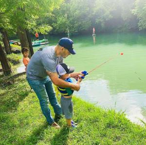 
a man standing next to a child on a lake at Geronimo Creek Retreat Getaway Cabin #3 in Seguin
