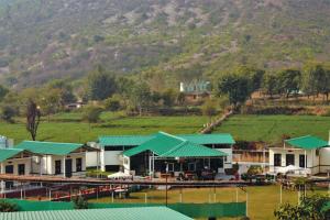 un complexe avec des toits verts et une montagne en arrière-plan dans l'établissement Shivir Aranya - Wilderness Resort, à Alwar