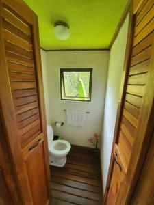 a small bathroom with a toilet and a window at Cabina Gan Eden - Walking distance from river in Portalón