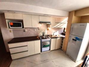 a small kitchen with a stove and a refrigerator at Zona Sur - Acogedor departamento completo - URBEANDINA in La Paz