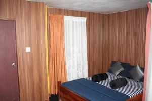 a bedroom with a bed with black pillows and a window at Bezel Bungalow Nuwara Eliya in Nuwara Eliya