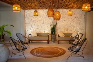 Noah Beach Hotel & Suites في ماهاهوال: غرفة معيشة مع كراسي وجدار حجري