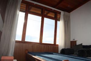 a bedroom with a bed with a large window at Bezel Bungalow Nuwara Eliya in Nuwara Eliya