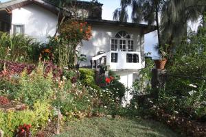 a white house with flowers in front of it at Bezel Bungalow Nuwara Eliya in Nuwara Eliya