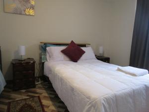 1 dormitorio con 1 cama grande con sábanas blancas y almohadas rojas en jazmines point, en Lima
