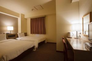 a hotel room with two beds and a desk at Sankei City Hotel Chiba in Chiba
