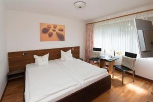 a bedroom with a large white bed and a desk at Hotel am Wasserturm in Flensburg