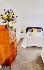 64 Mandalea B&B في Ohoka: غرفة نوم مع خزانة وسرير مع الزهور عليه