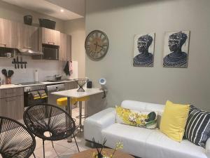 a living room with a white couch and a kitchen at Lovely Rosebank 1-bedroom condo with pool & cinema in Johannesburg
