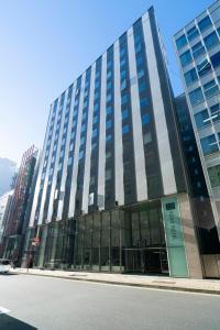 a tall building with glass windows on a street at KOKO HOTEL Ginza-1chome in Tokyo