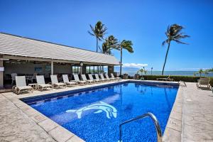 a swimming pool with chairs and the ocean in the background at High-End Resort Condo Nestled on Molokai Shoreline in Kaunakakai