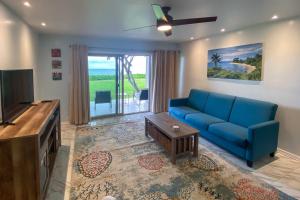 a living room with a blue couch and a tv at High-End Resort Condo Nestled on Molokai Shoreline in Kaunakakai