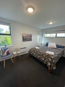 a bedroom with a bed and a chair and two windows at Bealey Avenue Apartment, 2 Bedroom apartment, Central City in Christchurch