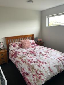 a bedroom with a bed with a floral bedspread and a window at Bealey Avenue Apartment, 2 Bedroom apartment, Central City in Christchurch