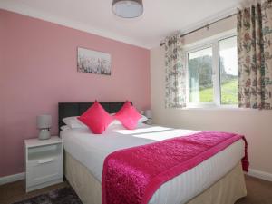 a bedroom with a bed with pink sheets and a window at Watergate Bay in Liskeard