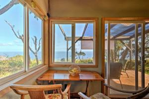 a room with windows and a wooden table and chairs at View House in Laupahoehoe with Patio and Ocean Views! in Papaaloa