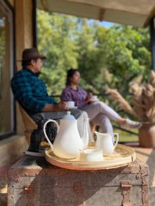 een man en een vrouw op een tafel met theepotten bij PaliGhar Farmstay in Kalimpong