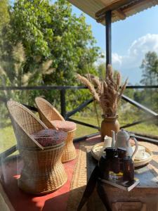 a table with wicker chairs on top of a balcony at PaliGhar Farmstay in Kalimpong