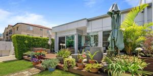 贝尔拉拉Keith's on Sylvan Beach, 1 of the 3 most popular units on Bribie的一座花园,在一座建筑前种植盆栽植物