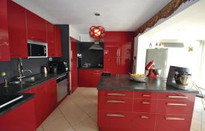 a red kitchen with black counters and red cabinets at Beautiful Home In Les Adrets With 5 Bedrooms, Wifi And Private Swimming Pool in Fréjus