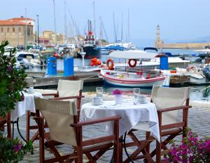 einen Tisch und Stühle mit Booten in einem Yachthafen in der Unterkunft Porto Veneziano Hotel in Chania