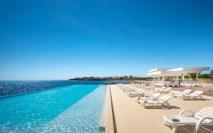 a swimming pool with lounge chairs and the ocean at Aminess Vival Maestral Hotel in Novigrad Istria