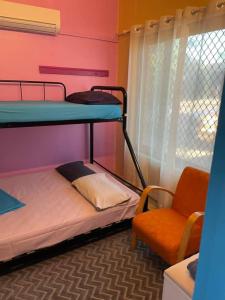 a dorm room with two bunk beds and a chair at The Cozy Hostel - Motel in Darwin
