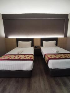 two beds sitting next to each other in a room at Palace Inn in Miri