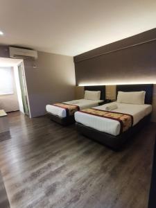 two beds in a room with wooden floors at Palace Inn in Miri
