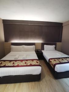 two beds in a hotel room with two at Palace Inn in Miri