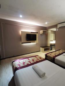 um quarto de hotel com duas camas e uma televisão de ecrã plano em Palace Inn em Miri