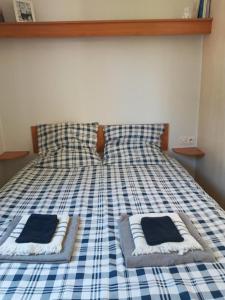 a bed with a blue and white checkered sheets and pillows at Mobil Home Saint Paul lès Dax in Saint-Paul-lès-Dax