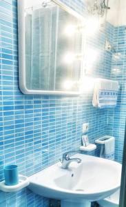 a blue tiled bathroom with a sink and a mirror at Vima's home in Naples