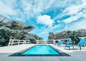 una piscina con 2 sillas azules y un cielo azul en Southport Sands en Southport