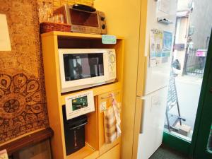 a kitchen with a microwave and a refrigerator at Nara Ugaya Guesthouse in Nara