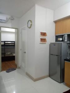 a kitchen with a refrigerator and a clock on the wall at Adel's Haven in Camella Northpoint in Davao City