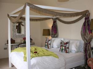 a bedroom with a white bed with a canopy at Lower Barns Guest House in Mevagissey