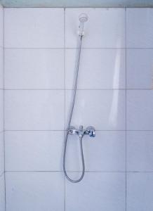 a shower with a hose on a white tile wall at Etana Motel Kampala in Kampala