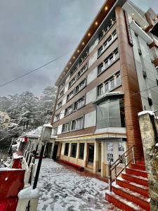 um grande edifício com neve em frente em Hotel Victory em Shimla