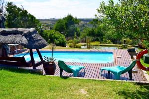 a swimming pool with two chairs and a umbrella at A Vie at C Self Catering House in Bothastrand