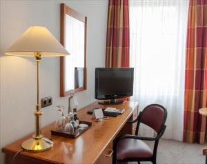 a room with a desk with a television and a lamp at Hotel Zumnorde Am Anger in Erfurt