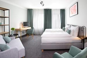 ミュンヘンにあるホテル ロートクロイツプラッツのベッド2台とデスクが備わるホテルルームです。